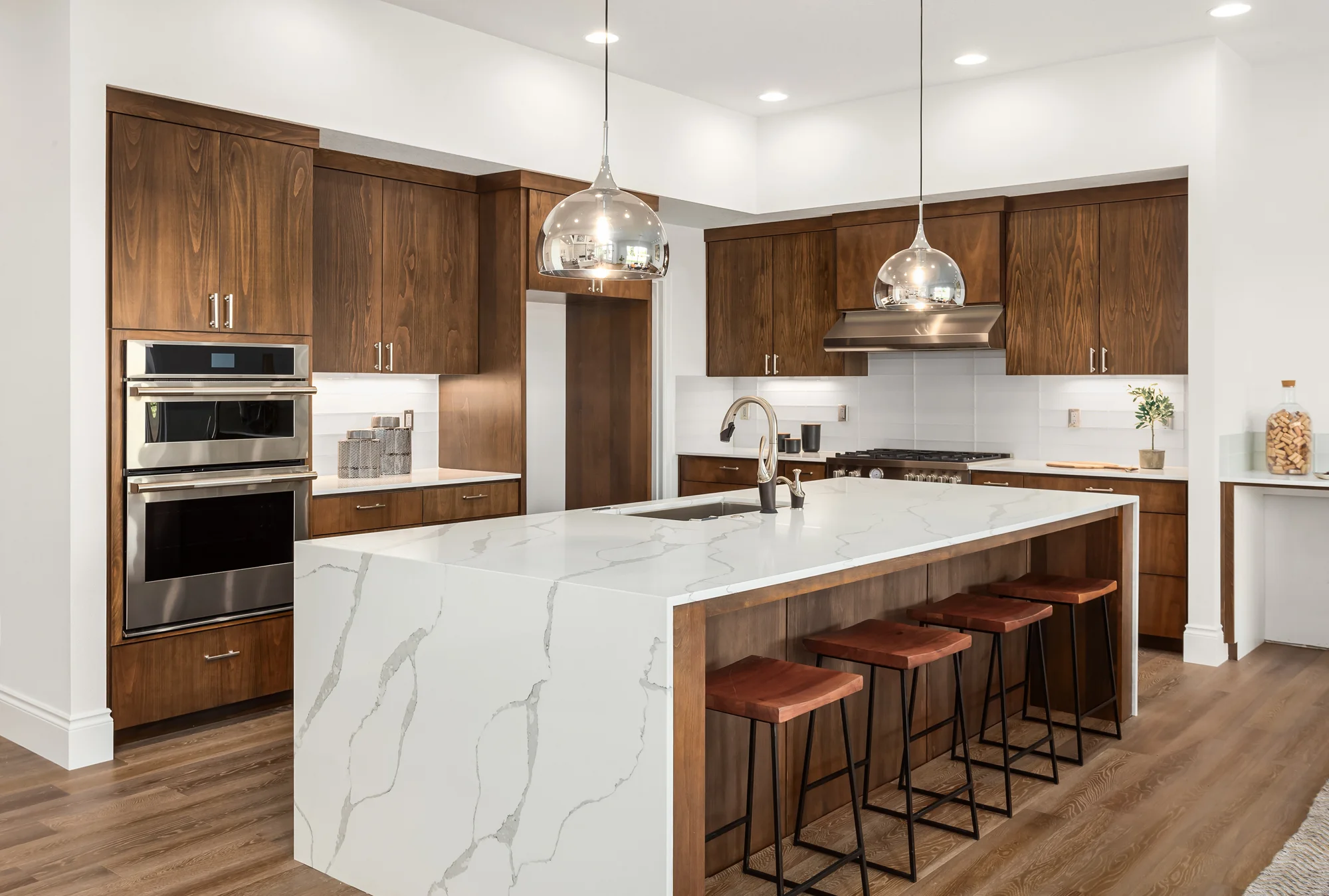 Kitchen design inspiration with a stone waterfall island and rich wood cabinetry